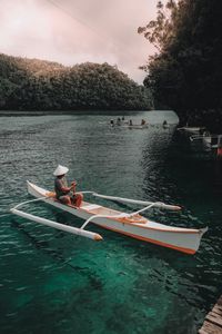 People rowing boat in river against sky