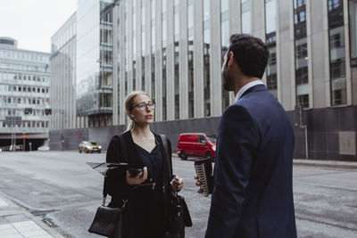 Female entrepreneur with bag talking to coworker in city