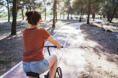 Woman riding bicycle at countryside during sunny day