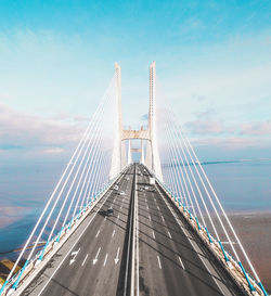 Suspension bridge in city against sky