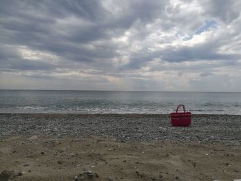 Red bag at beach against sky