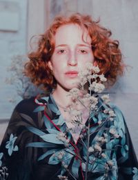 Portrait of young woman standing against wall