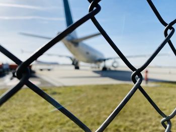 Close-up of airplane seen through chainlink fence