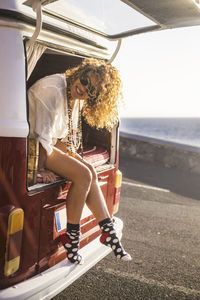 Portrait of smiling woman with curly hair sitting on motor home