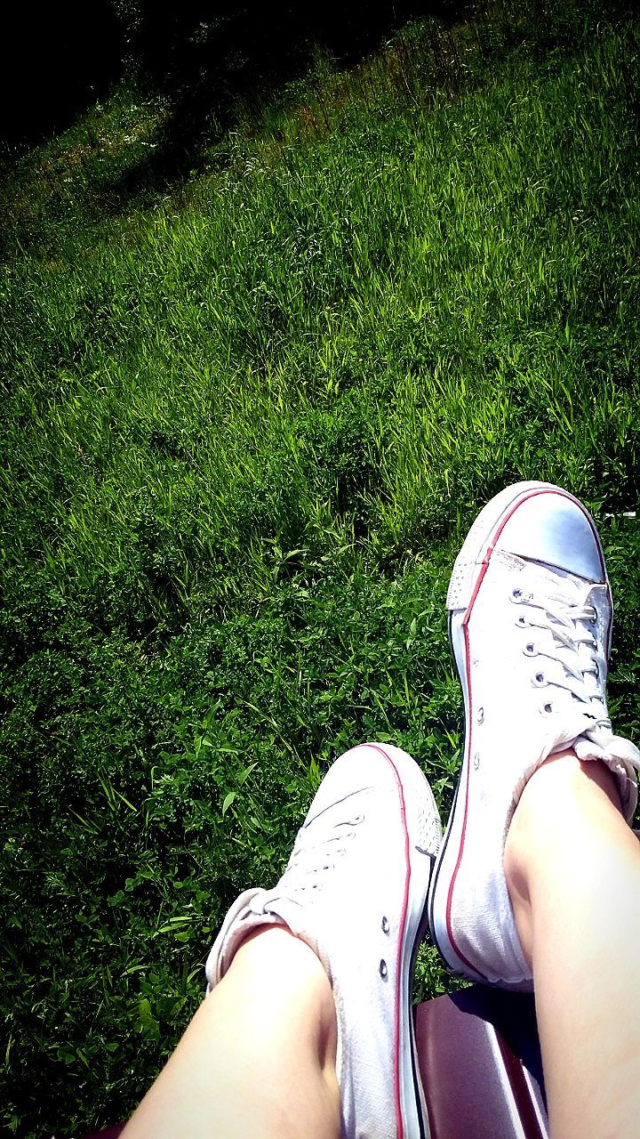 LOW SECTION OF WOMAN STANDING ON GRASSY FIELD