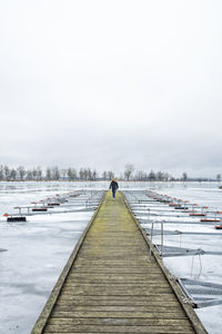 Man on pier against sky during winter