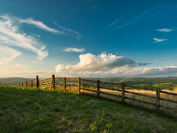 Wooden fence on field against sky