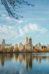 Buildings by river against sky