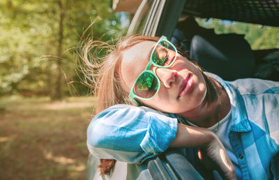 Young woman wearing sunglasses traveling in car