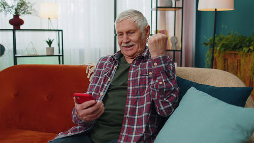 Young woman using mobile phone while sitting on sofa at home