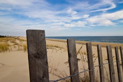 Wooden posts on beach against sky