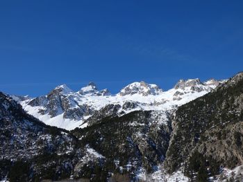 Scenic view of snowcapped mountains against clear blue sky