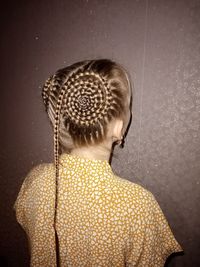 Portrait of a young girl facing the wall with a beautiful braiding of hair on her head
