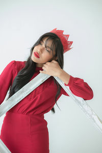 Portrait of young woman standing against white background