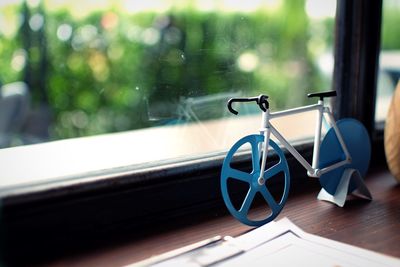 Close-up of small bicycle decor by window