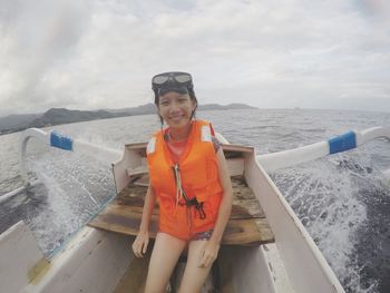 Portrait of smiling woman sitting on boat in sea against sky