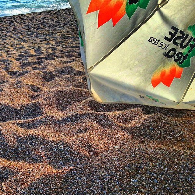 beach, sand, identity, flag, transportation, multi colored, shore, day, high angle view, red, no people, outdoors, sunlight, communication, text, sea, national flag, number, close-up, patriotism