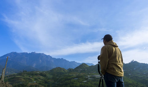 Rear view of man looking at mountain against sky