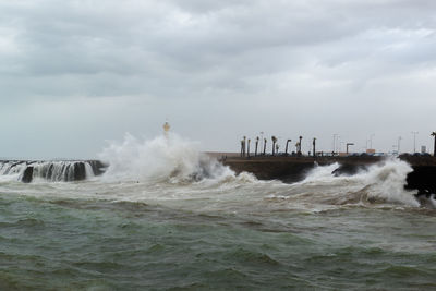 Waves splashing on shore against sky