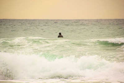 Man surfing in sea against clear sky