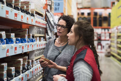 Saleswoman assisting female customer in hardware store