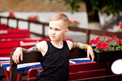 Boy looking away at red flower