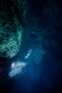 Man scuba diving by rock formation in sea at gozo