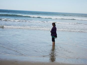 Full length of woman standing on beach against sky