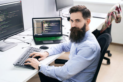 Side view of woman using laptop at office