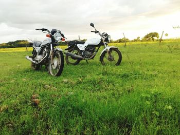 Motorcycles parked on field against sky