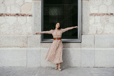 Woman with arms outstretched standing by window