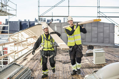 Construction workers carrying wooden planks at site