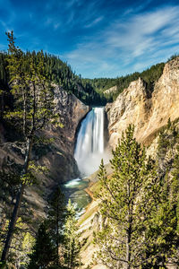 Scenic view of waterfall in forest against sky