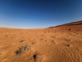 Scenic view of desert against clear blue sky