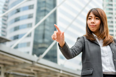 Young businesswoman gesturing while standing in city