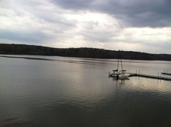 Boats in lake against cloudy sky