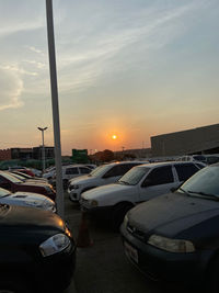 Cars in parking lot against sky during sunset