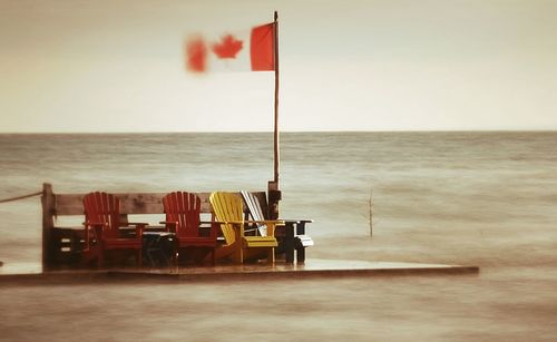 Chairs and tables by sea against sky