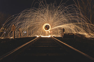 Person performing light painting on railroad track at night