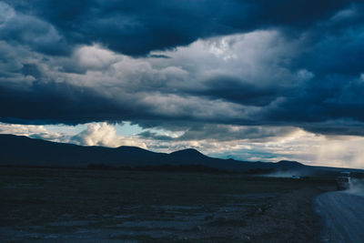 Scenic view of landscape against storm clouds