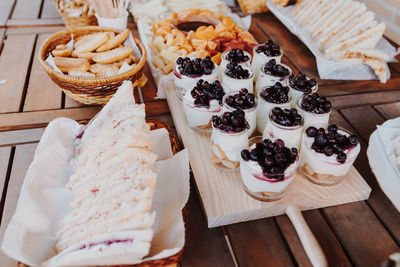 Donuts, yogurt, fruits fondue tangerine, banana, kiwi, blueberries, strawberries on a wooden table