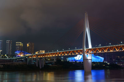 Illuminated bridge over river against sky in city at night