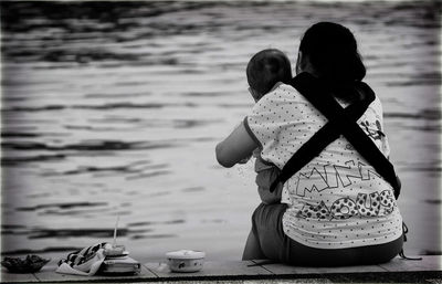 Rear view of couple sitting on shore