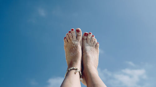 Low angle view of woman feet against sky