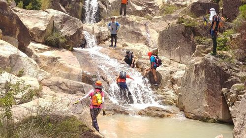 People walking on rocks against mountain