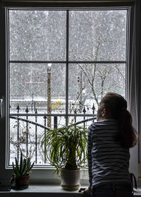 Rear view of girl looking through window