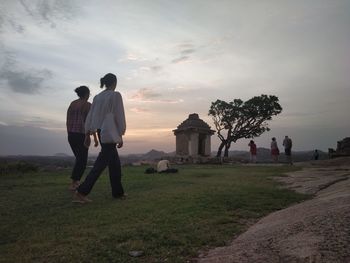 Men on field against sky during sunset