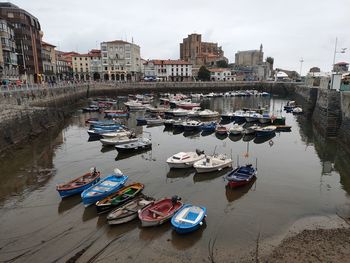 High angle view of boats moored at harbor by buildings in city