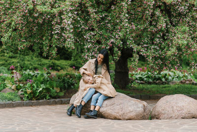 Rear view of woman sitting on rock