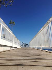 Low angle view of footbridge against clear blue sky